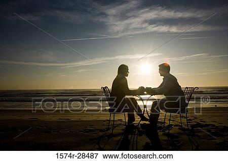 Silhouette of a couple relaxing on a beach View Large Photo Image Stock Photo - Silhouette of a couple relaxing on a beach. Fotosearch