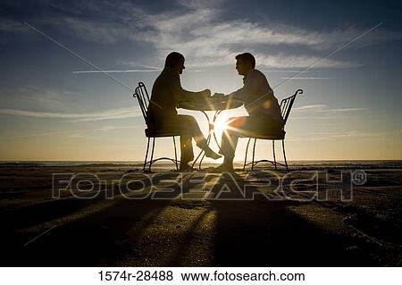 Silhouette of a couple relaxing on a beach View Large Photo Image Stock Photo - Silhouette of a couple relaxing on a beach. Fotosearch