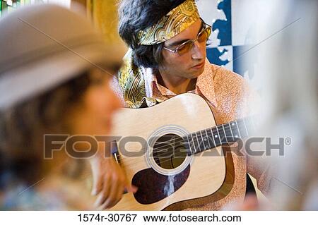 Stock Photo - Sister in foreground while young man playing guitar. Fotosearch