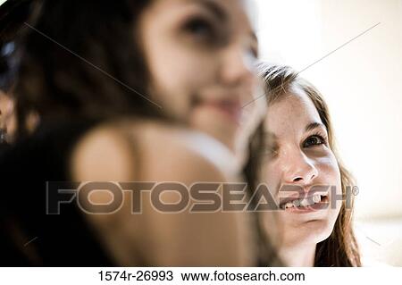 Stock Image - Sisters smiling and looking away. Fotosearch