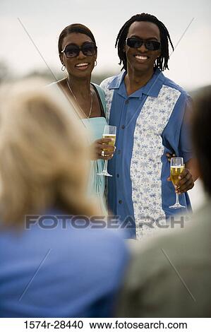 Smiling mid adult couple standing with glass of champagne View Large Photo Image Stock Image - Smiling mid adult couple standing with glass of champagne. Fotosearch