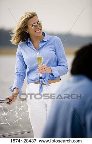 Smiling mid adult woman standing with glass of champagne View Large Photo Image Stock Photo - Smiling mid adult woman standing with glass of champagne. Fotosearch