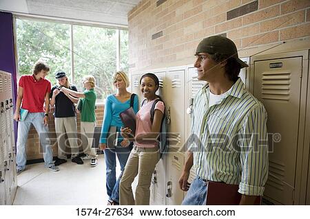 Picture - Students smiling and standing by lockers in corridor. Fotosearch