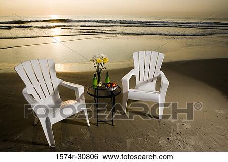 Table with chairs arranged on the beach with sunset in background View Large Photo Image Stock Photograph - Table with chairs arranged on the beach with sunset in background. Fotosearch