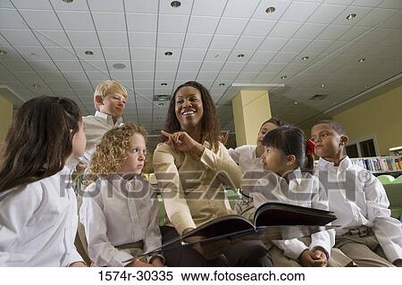 Teacher holding a book and pointing towards a student in the library View Large Photo Image Stock Photography - Teacher holding a book and pointing towards a student in the library. Fotosearch