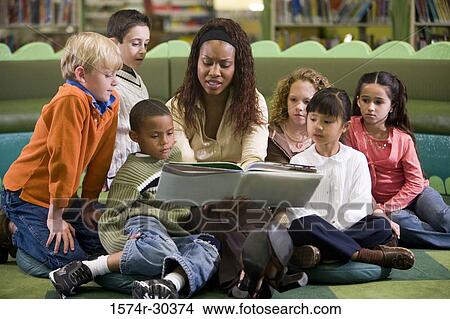 Teacher reading out to students in the library View Large Photo Image Picture - Teacher reading out to students in the library. Fotosearch
