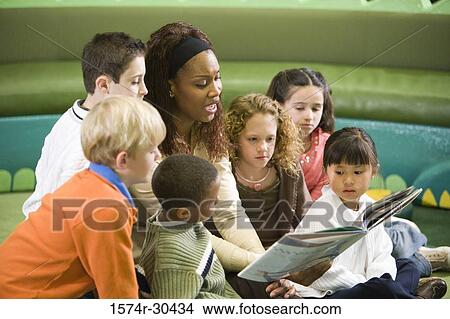 Teacher reading out to students in the library View Large Photo Image Picture - Teacher reading out to students in the library. Fotosearch