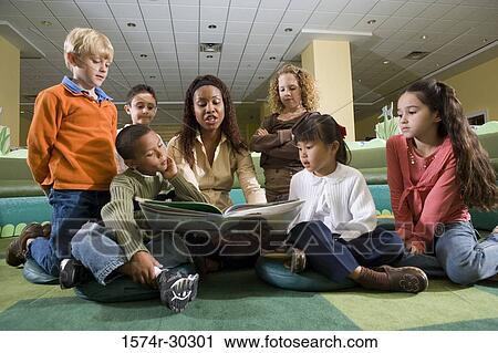 Teacher reading out to students in the library View Large Photo Image Stock Image - Teacher reading out to students in the library. Fotosearch