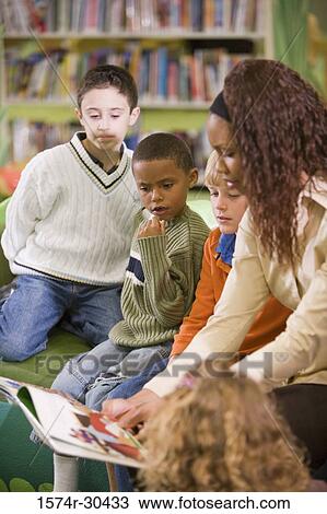 Teacher reading out to students in the library View Large Photo Image Stock Image - Teacher reading out to students in the library. Fotosearch