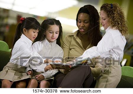 Teacher reading out to students in the library View Large Photo Image Stock Photo - Teacher reading out to students in the library. Fotosearch
