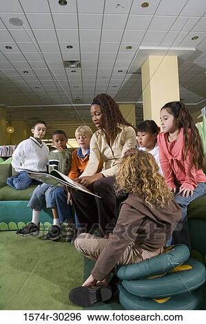 Teacher reading out to students in the library View Large Photo Image Stock Photograph - Teacher reading out to students in the library. Fotosearch