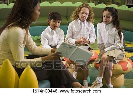 Teacher showing a book to schoolgirls in the library View Large Photo Image Stock Photograph - Teacher showing a book to schoolgirls in the library. Fotosearch