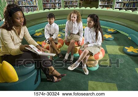Picture - Teacher showing book to schoolgirls in the library. Fotosearch