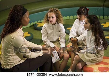 Teacher sitting with schoolgirls in the library View Large Photo Image Picture - Teacher sitting with schoolgirls in the library. Fotosearch