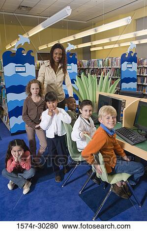 Teacher standing with schoolboys and girls by computers in the library View Large Photo Image Stock Image - Teacher standing with schoolboys and girls by computers in the library. Fotosearch