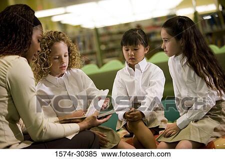 Stock Photography - Teacher teaching schoolgirls in the library. Fotosearch