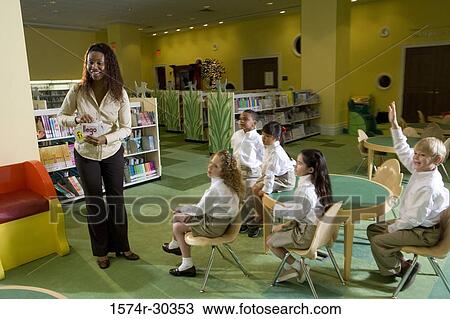 Stock Image - Teacher with students in the library. Fotosearch