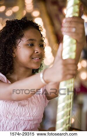 Teenage girl holding a pole in a carousel View Large Photo Image Stock Photography - Teenage girl holding a pole in a carousel. Fotosearch