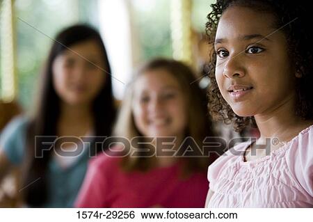 Teenage girl looking away with friends smiling in the background View Large Photo Image Stock Photograph - Teenage girl looking away with friends smiling in the background. Fotosearch