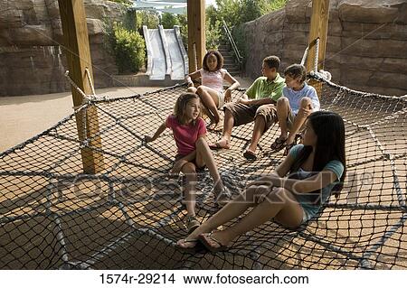 Teenagers sitting on net tied to the wooden columns View Large Photo Image Picture - Teenagers sitting on net tied to the wooden columns. Fotosearch