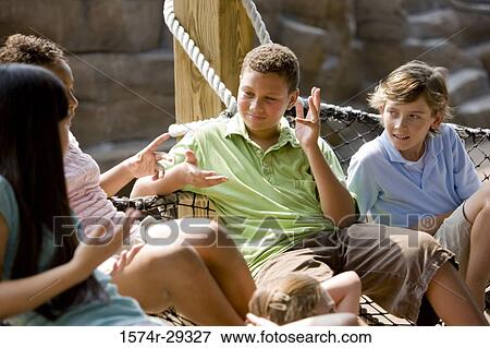 Stock Photo - Teenagers sitting on net tied to wooden columns. Fotosearch