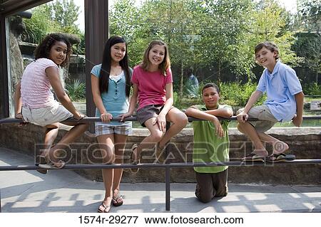 Stock Photo - Teenagers sitting on the iron railings. Fotosearch