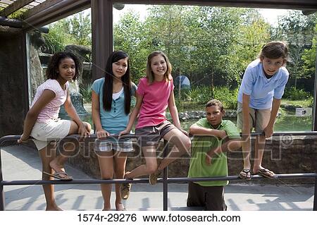 Stock Photograph - Teenagers sitting on the iron railings. Fotosearch