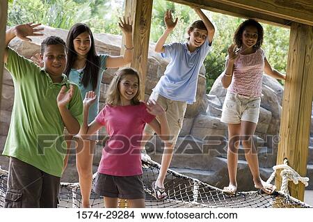 Teenagers standing on net tied to the wooden columns and waving hands View Large Photo Image Picture - Teenagers standing on net tied to the wooden columns and waving hands. Fotosearch