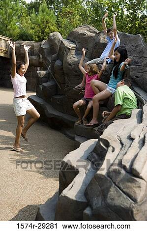 Teenagers with their arms raised sitting on rocks and playing View Large Photo Image Stock Image - Teenagers with their arms raised sitting on rocks and playing. Fotosearch