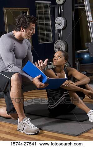 Trainer and a young woman engaged in conversion in the gym View Large Photo Image Stock Image - Trainer and a young woman engaged in conversion in the gym. Fotosearch