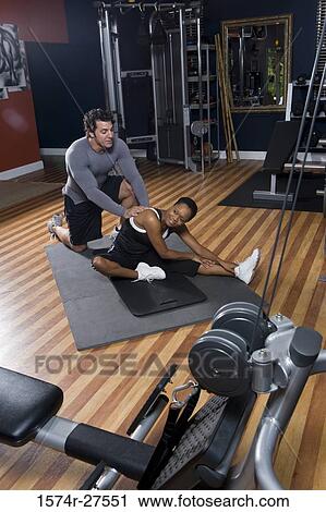 Trainer helping out of a young woman in the gym View Large Photo Image Stock Image - Trainer helping out of a young woman in the gym. Fotosearch