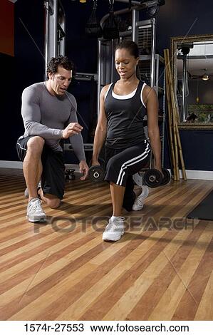 Trainer instructing a young woman in the gym View Large Photo Image Stock Image - Trainer instructing a young woman in the gym. Fotosearch
