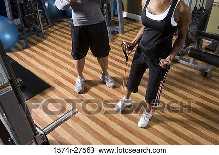 Trainer instructing a young woman in the gym View Large Photo Image Stock Image - Trainer instructing a young woman in the gym. Fotosearch