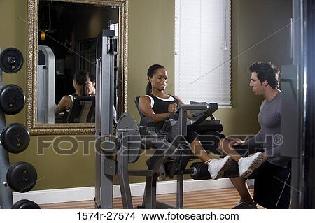 Trainer instructing a young woman with sports equipment in the gym View Large Photo Image Picture - Trainer instructing a young woman with sports equipment in the gym. Fotosearch