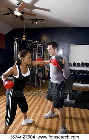 Trainer instructing a young woman with boxing equipment in the gym View Large Photo Image Picture - Trainer instructing a young woman with boxing equipment in the gym. Fotosearch
