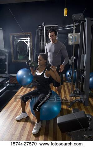 Trainer instructing a young woman with sports equipment in the gym View Large Photo Image Stock Image - Trainer instructing a young woman with sports equipment in the gym. Fotosearch