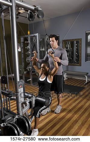 Trainer instructing a young woman with sports equipment in the gym View Large Photo Image Stock Image - Trainer instructing a young woman with sports equipment in the gym. Fotosearch