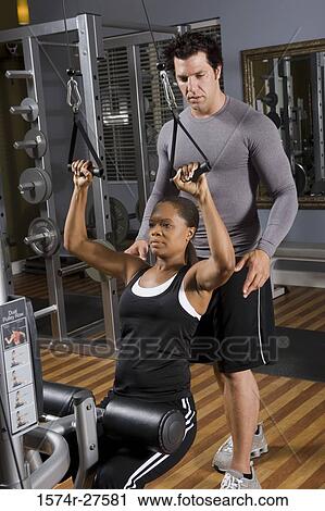 Trainer instructing a young woman with sports equipment in the gym View Large Photo Image Stock Image - Trainer instructing a young woman with sports equipment in the gym. Fotosearch