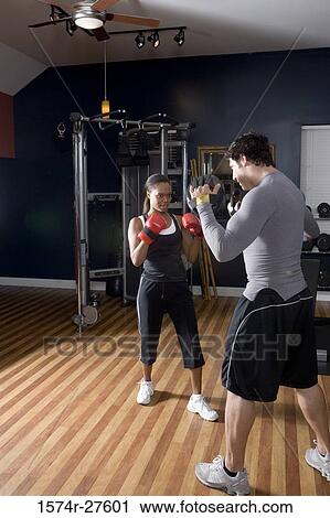 Trainer instructing a young woman with boxing equipment in the gym View Large Photo Image Stock Image - Trainer instructing a young woman with boxing equipment in the gym. Fotosearch
