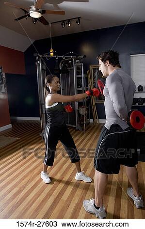 Trainer instructing a young woman with boxing equipment in the gym View Large Photo Image Stock Image - Trainer instructing a young woman with boxing equipment in the gym. Fotosearch