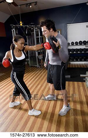 Trainer instructing a young woman with boxing equipment in the gym View Large Photo Image Stock Image - Trainer instructing a young woman with boxing equipment in the gym. Fotosearch