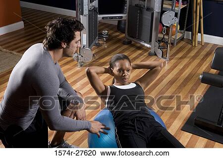 Trainer instructing a young woman with fitness ball in the gym View Large Photo Image Stock Image - Trainer instructing a young woman with fitness ball in the gym. Fotosearch