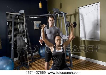 Trainer instructing a young woman with sports equipment in the gym View Large Photo Image Stock Photo - Trainer instructing a young woman with sports equipment in the gym. Fotosearch