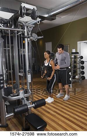 Trainer instructing a young woman with sports equipment in the gym View Large Photo Image Stock Photo - Trainer instructing a young woman with sports equipment in the gym. Fotosearch