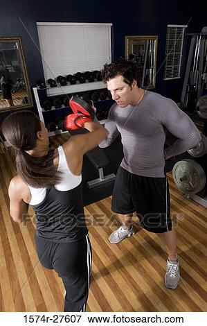 Trainer instructing a young woman with boxing equipment in the gym View Large Photo Image Stock Photo - Trainer instructing a young woman with boxing equipment in the gym. Fotosearch
