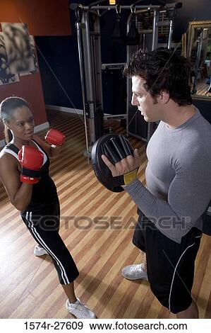 Trainer instructing a young woman with boxing equipment in the gym View Large Photo Image Stock Photo - Trainer instructing a young woman with boxing equipment in the gym. Fotosearch