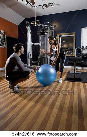 Trainer instructing a young woman with fitness ball in the gym View Large Photo Image Stock Photograph - Trainer instructing a young woman with fitness ball in the gym. Fotosearch