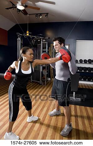 Trainer instructing a young woman with boxing equipment in the gym View Large Photo Image Stock Photography - Trainer instructing a young woman with boxing equipment in the gym. Fotosearch