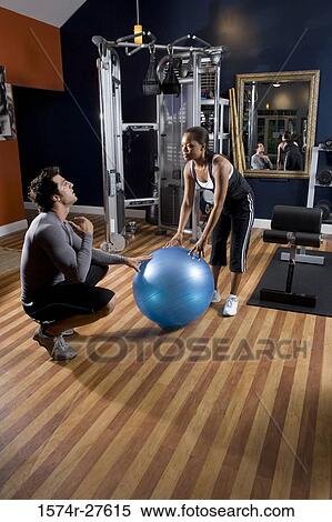 Trainer instructing a young woman with fitness ball in the gym View Large Photo Image Stock Photography - Trainer instructing a young woman with fitness ball in the gym. Fotosearch