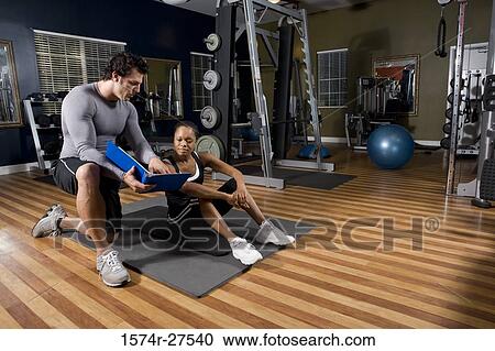 Trainer showing a file to a young woman in the gym View Large Photo Image Stock Image - Trainer showing a file to a young woman in the gym. Fotosearch